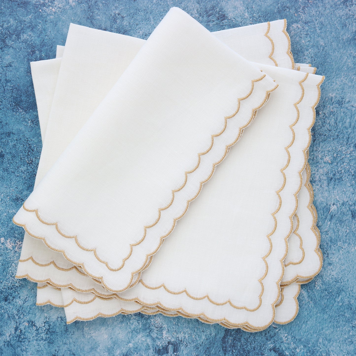 White napkins with gold metallic scallops on blue background