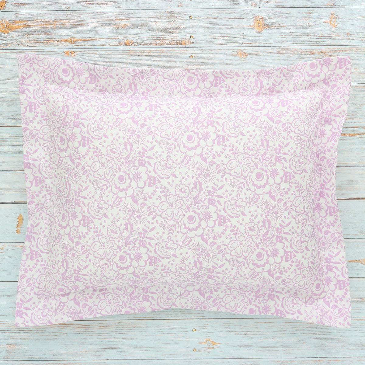 A boudoir sham with a small floral Liberty London print in violet and white, displayed on a wooden surface.