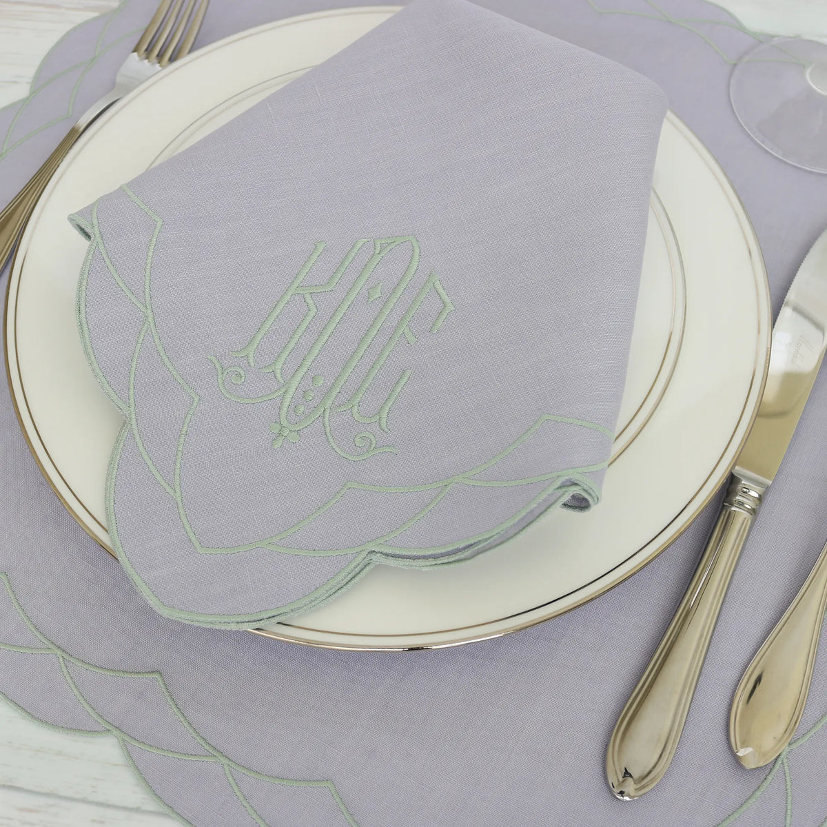 Table setting with a Lavender Cosmo napkin, silverware, and Cosmo placemat on a wooden table.