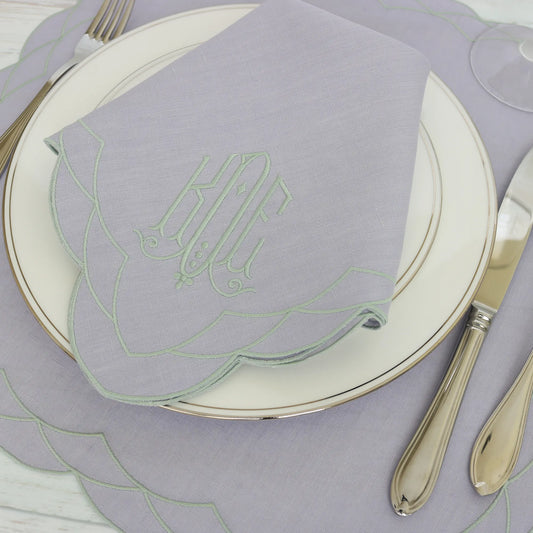 Table setting with a Lavender Cosmo napkin, silverware, and Cosmo placemat on a wooden table.