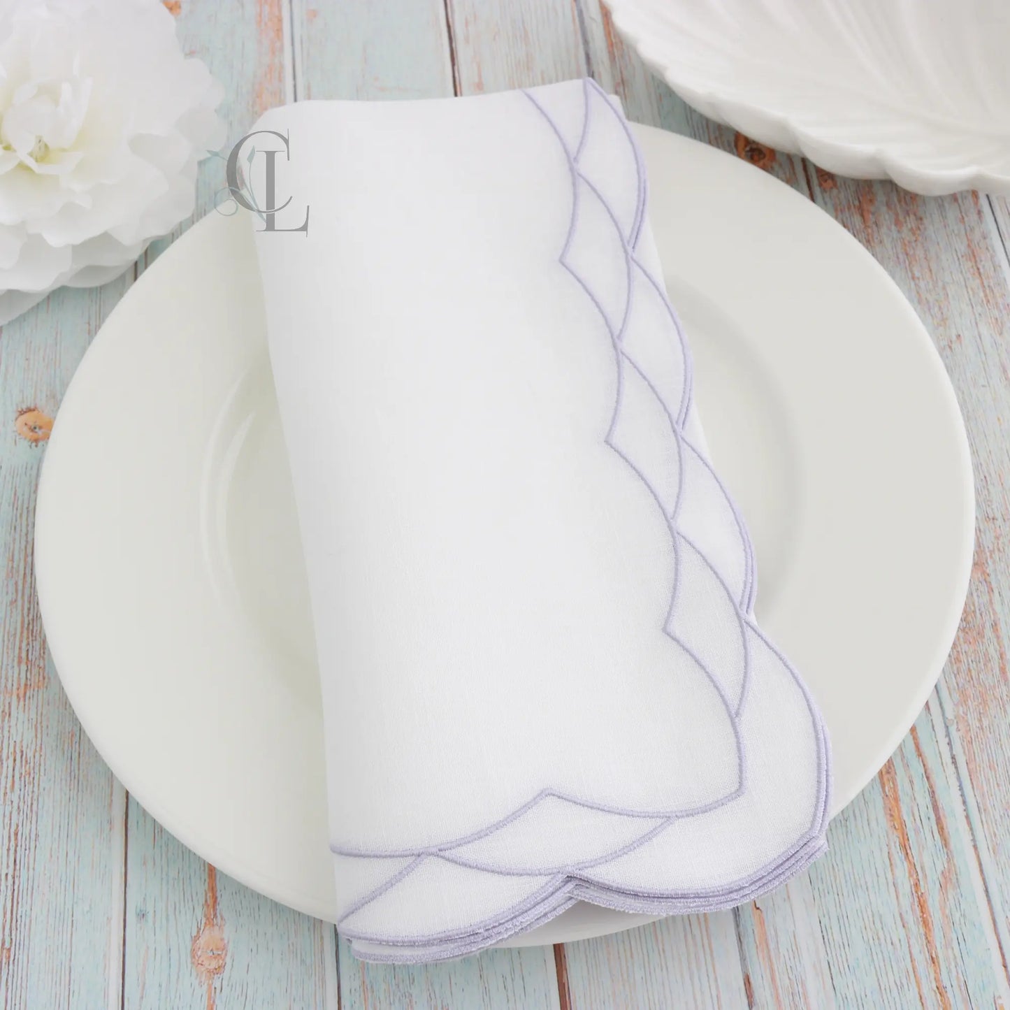White plate with Lavender Cosmo decorative border on a White dinner napkin, featuring 'Cora's Linen' branding.