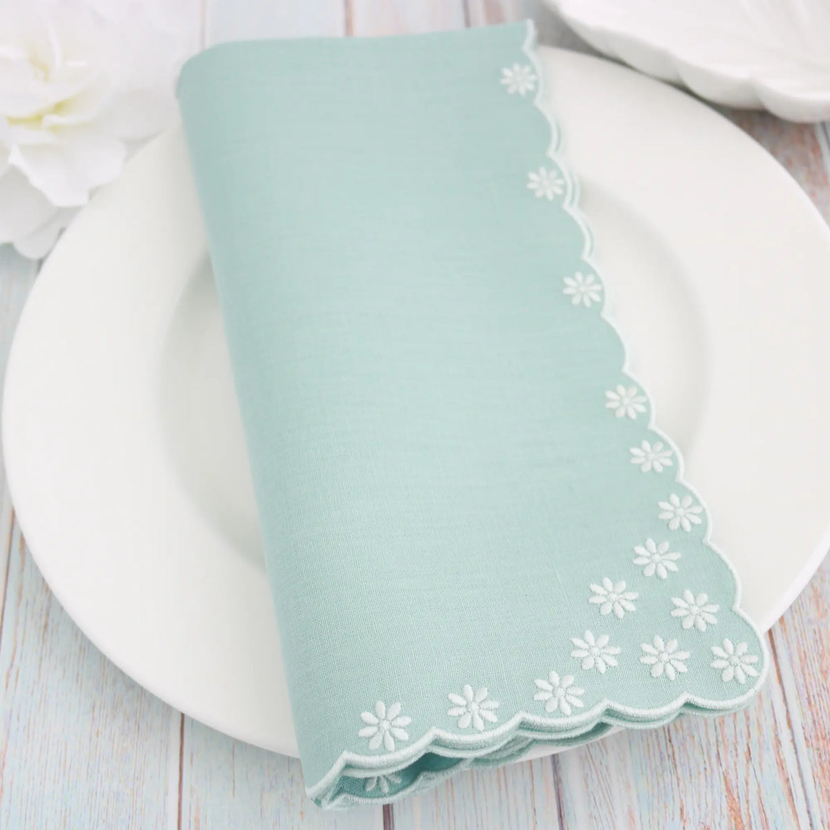 Harbor Green embroidered napkin with floral patterns on a white plate