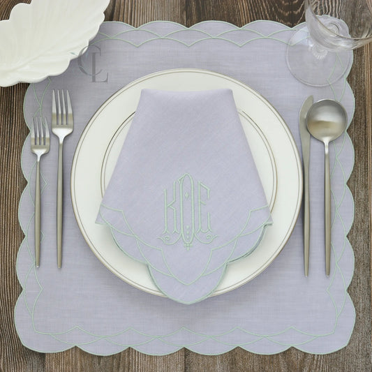 Table setting with a Lavender Cosmo napkin, silverware, and Cosmo placemat on a wooden table.