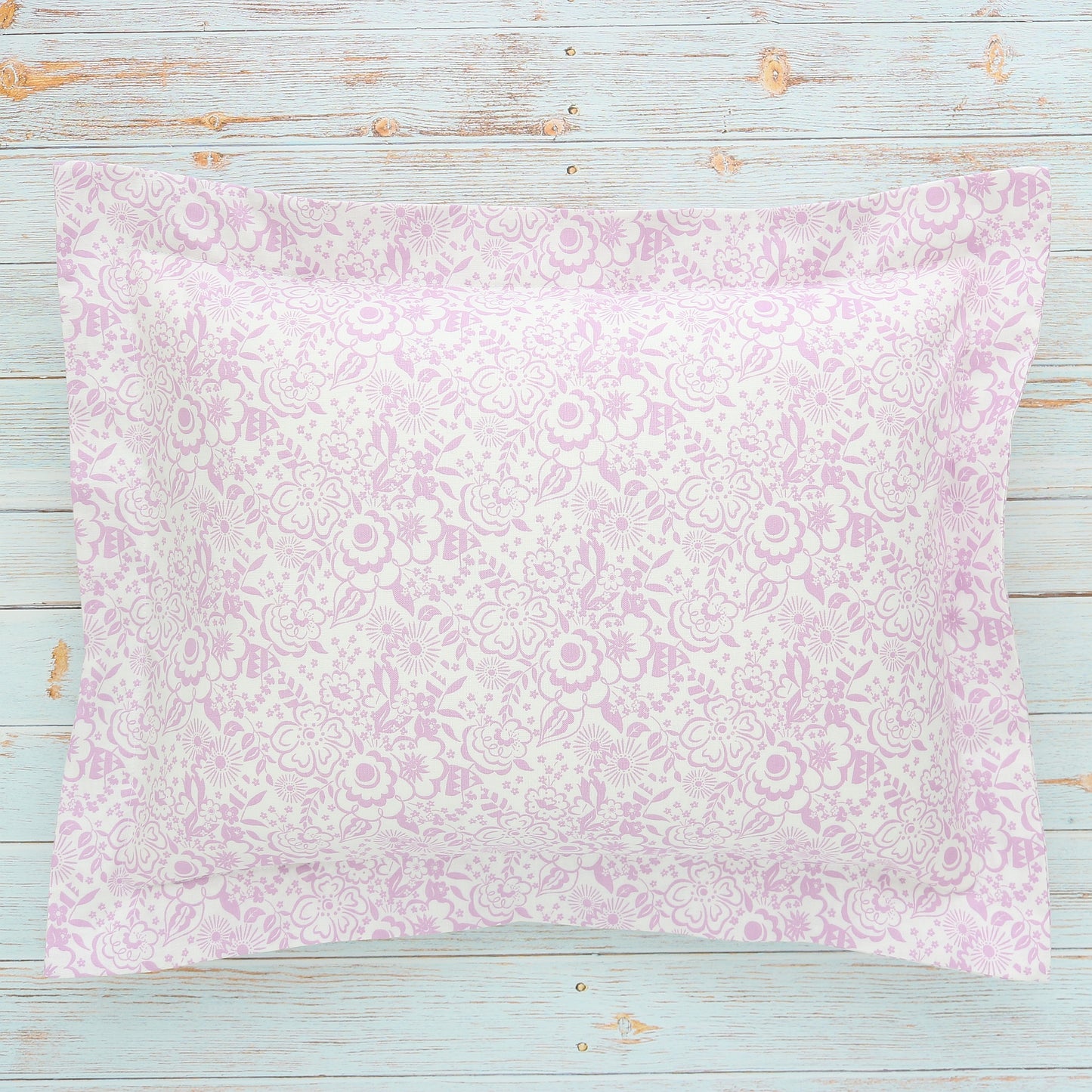 A boudoir sham with a small floral Liberty London print in violet and white, displayed on a wooden surface.