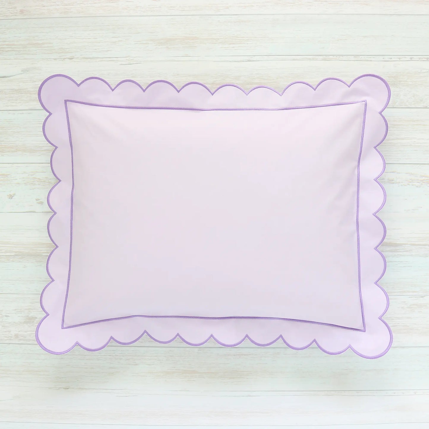 Scalloped Lilac pillow on a light wooden surface
