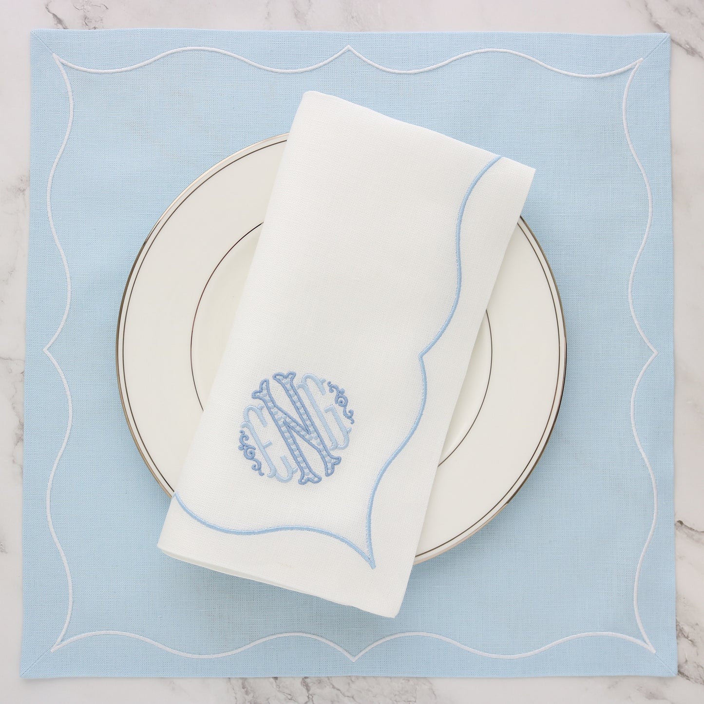 Caroline monogram ENG on a white Gabriella linen dinner napkin with plate with a Baby Blue Gabriella placemat