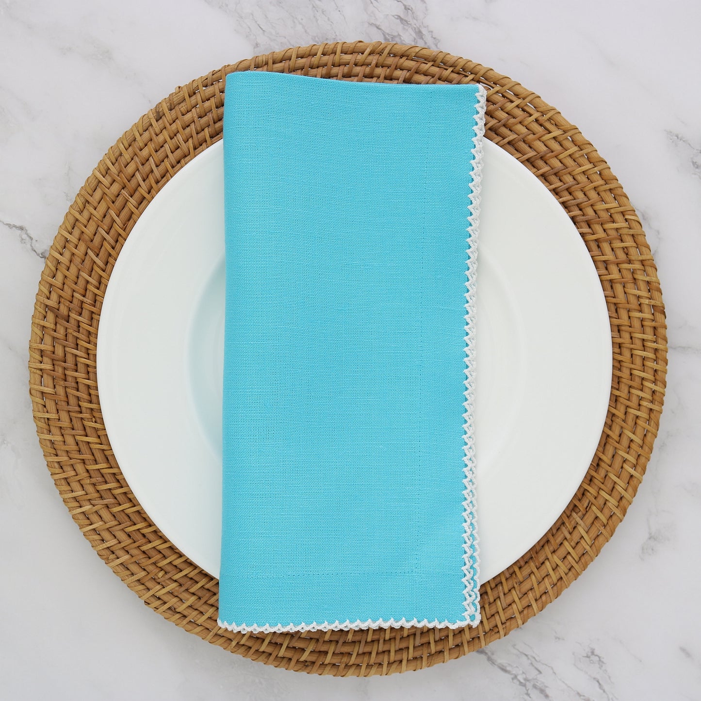 Aqua napkin with white picot trim on plate with charger