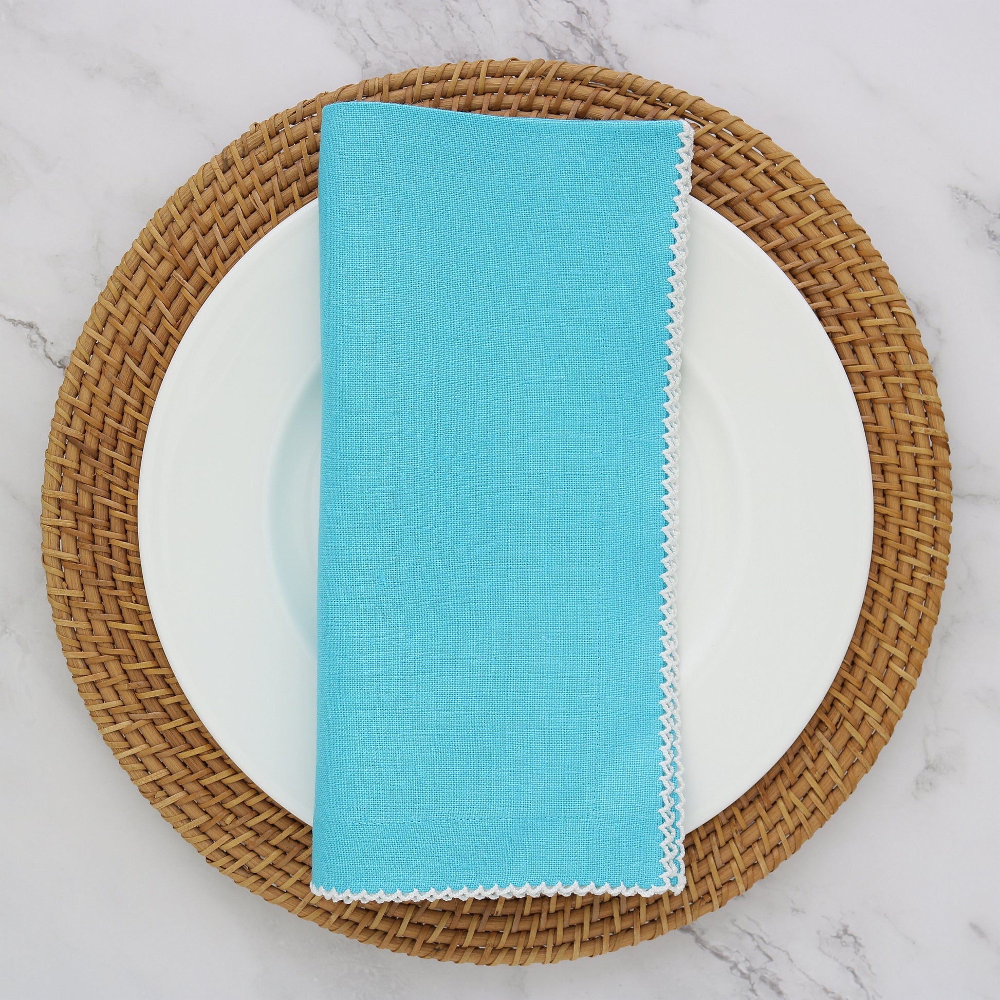 Aqua napkin with white picot trim on plate with charger