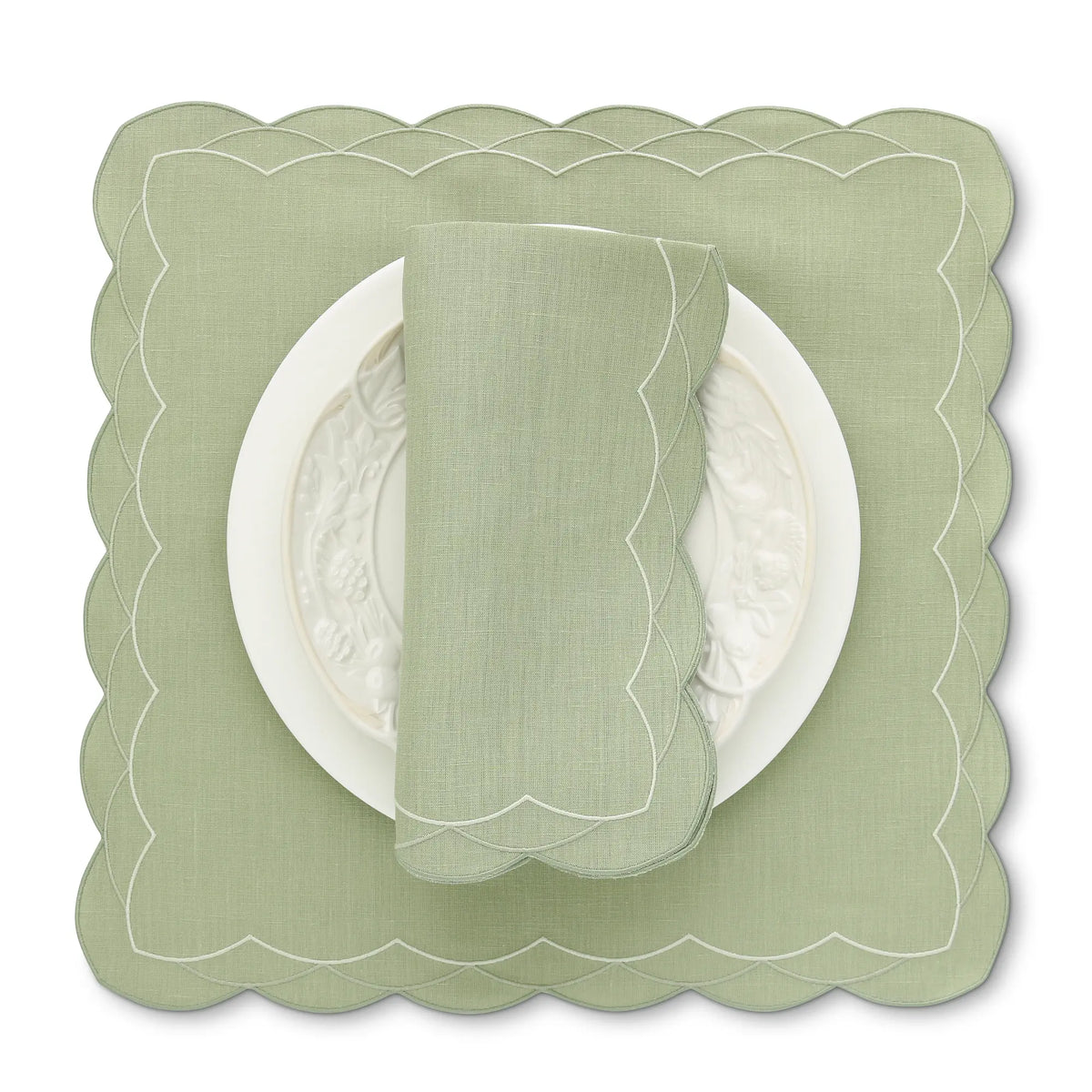 Green scalloped Cosmo placemat with a matching napkin on a white background