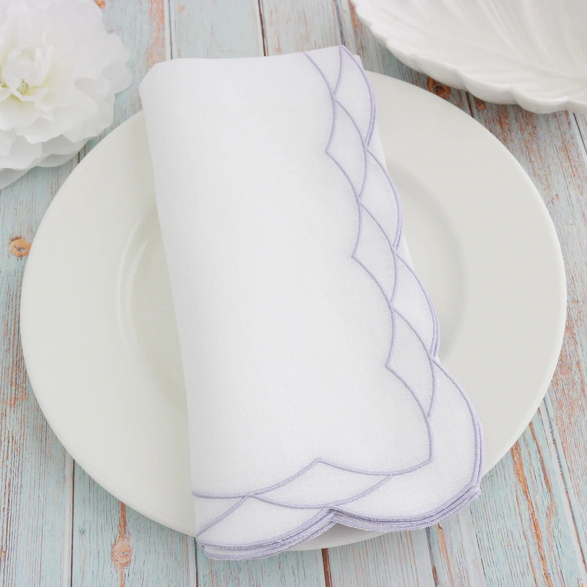 White plate with Lavender Cosmo decorative border on a White dinner napkin, featuring 'Cora's Linen' branding.