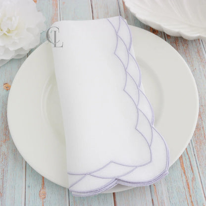 White plate with Lavender Cosmo decorative border on a White dinner napkin, featuring 'Cora's Linen' branding.