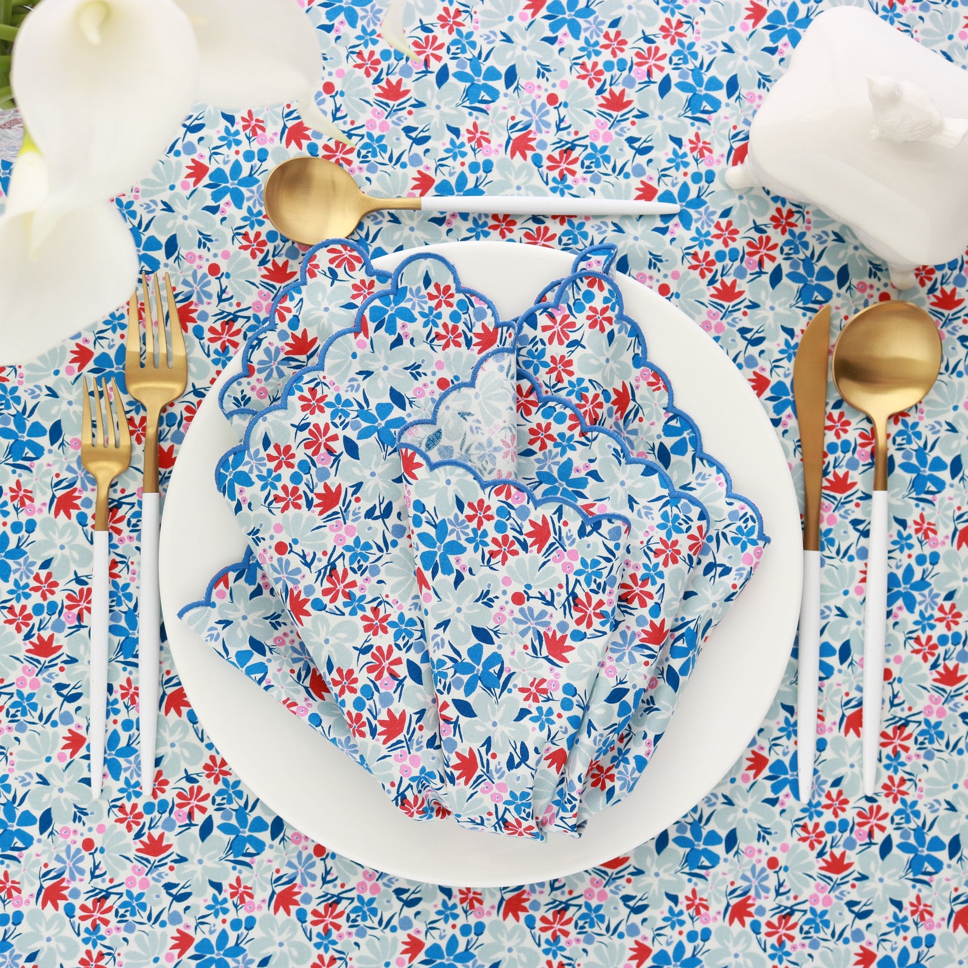 tablescape featuring a Liberty London print tablecloth and scalloped dinner napkin