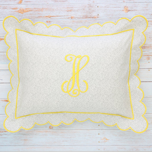 A rectangular boudoir sham with a small floral print and scalloped yellow edge, featuring a monogrammed letter 'H' in the center.