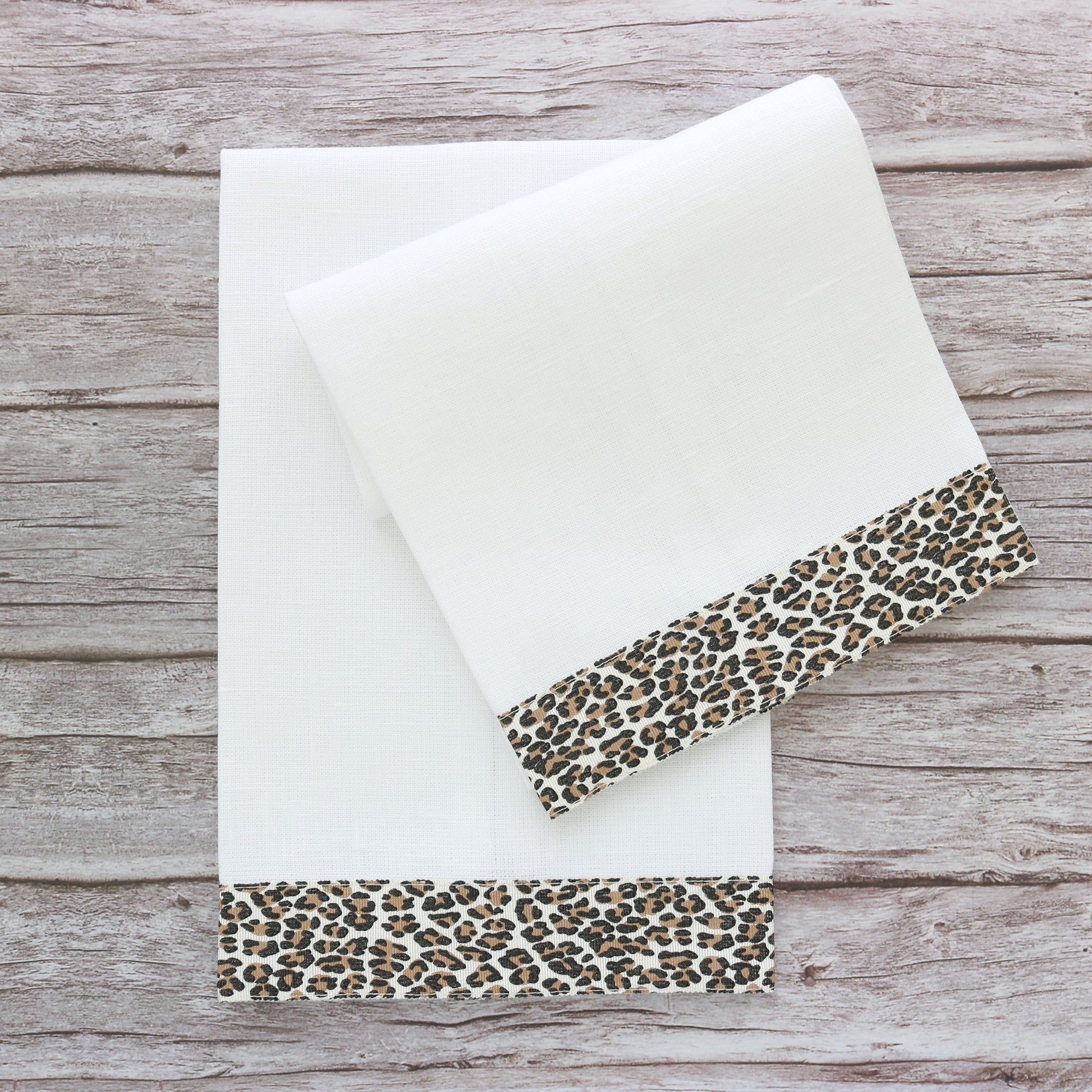 set of two white linen guest towels with cheetah print ribbon border