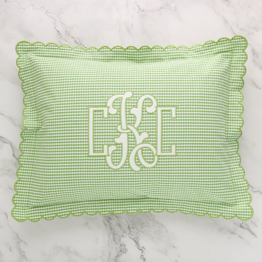 Green and white seersucker scalloped boudoir sham with monogram CKC in White on the front, placed on a marble surface.