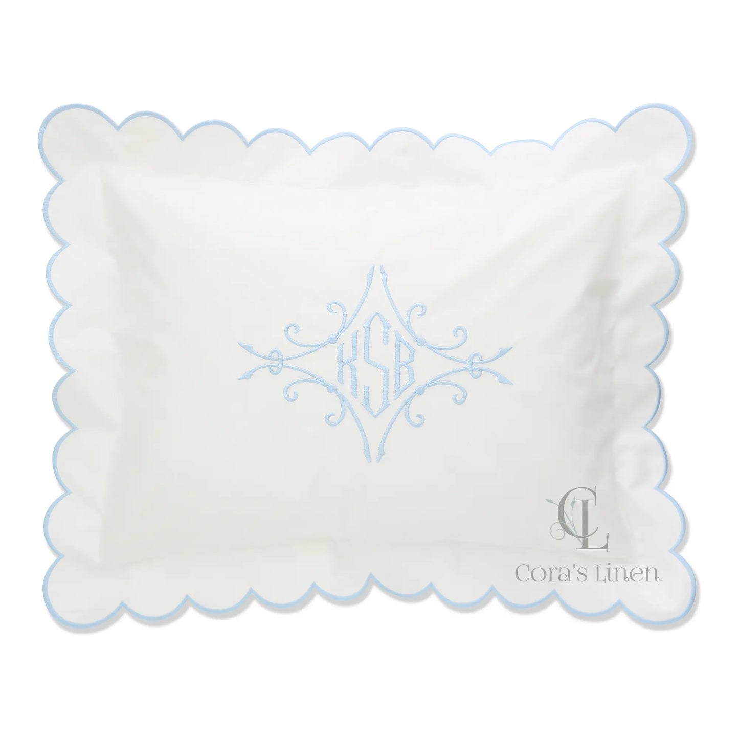 A scalloped percale boudoir sham with a monogram KSB in the center, displayed in white with blue detailing.