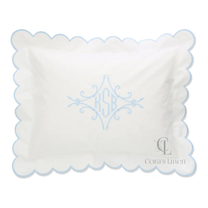 A scalloped percale boudoir sham with a monogram KSB in the center, displayed in white with blue detailing.