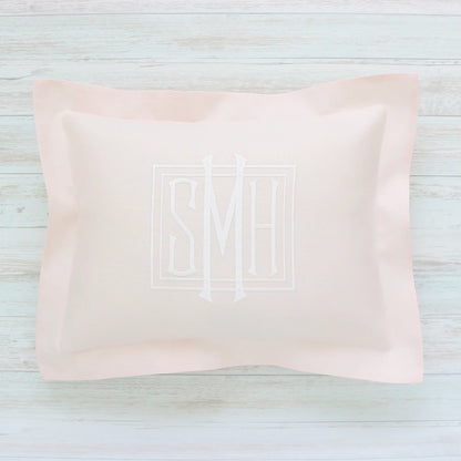 Pink pillow with monogram SMH on a light wooden surface