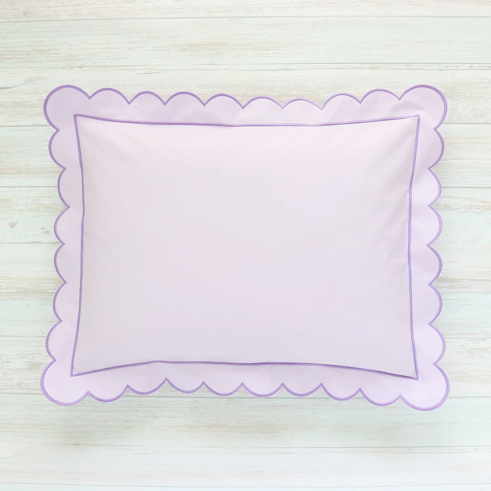 Scalloped Lilac pillow on a light wooden surface