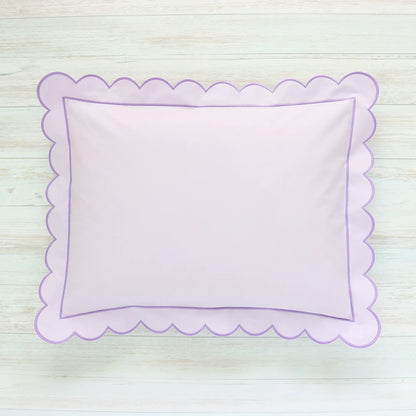 Scalloped Lilac pillow on a light wooden surface