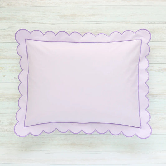Scalloped Lilac pillow on a light wooden surface