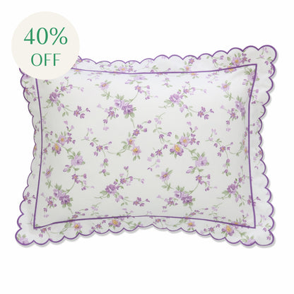 A scalloped boudoir sham with a floral print featuring purple flowers and a scalloped purple edge.